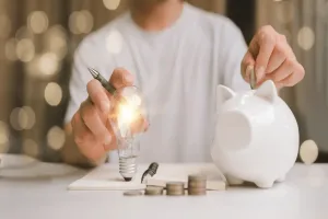 Economia de energia representada por lâmpada acesa e cofrinho para guardar dinheiro
