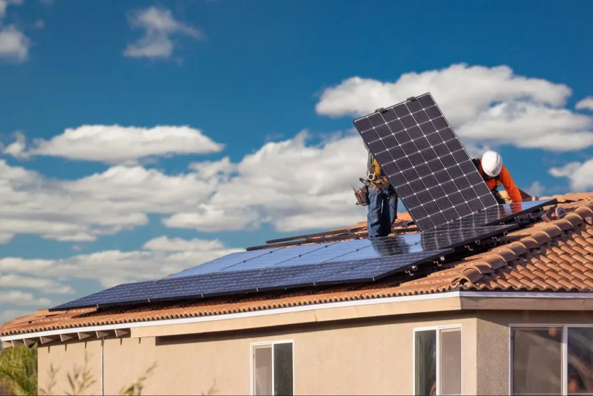Dois homens no telhado de uma casa, instalando um painel de energia solar