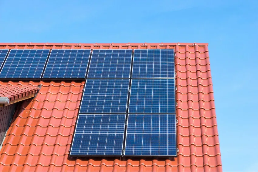 Painel de módulo fotovoltaico apoiado em cima de telhado laranja de casa